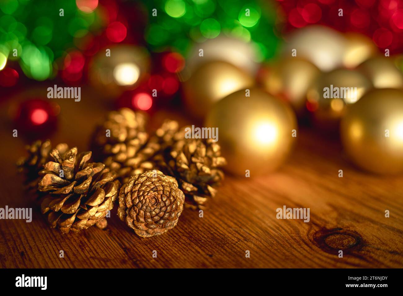 Nature morte de Noël avec des pommes de pin dorées et des boules et des guirlandes sur la table en bois et la lumière dorée Banque D'Images