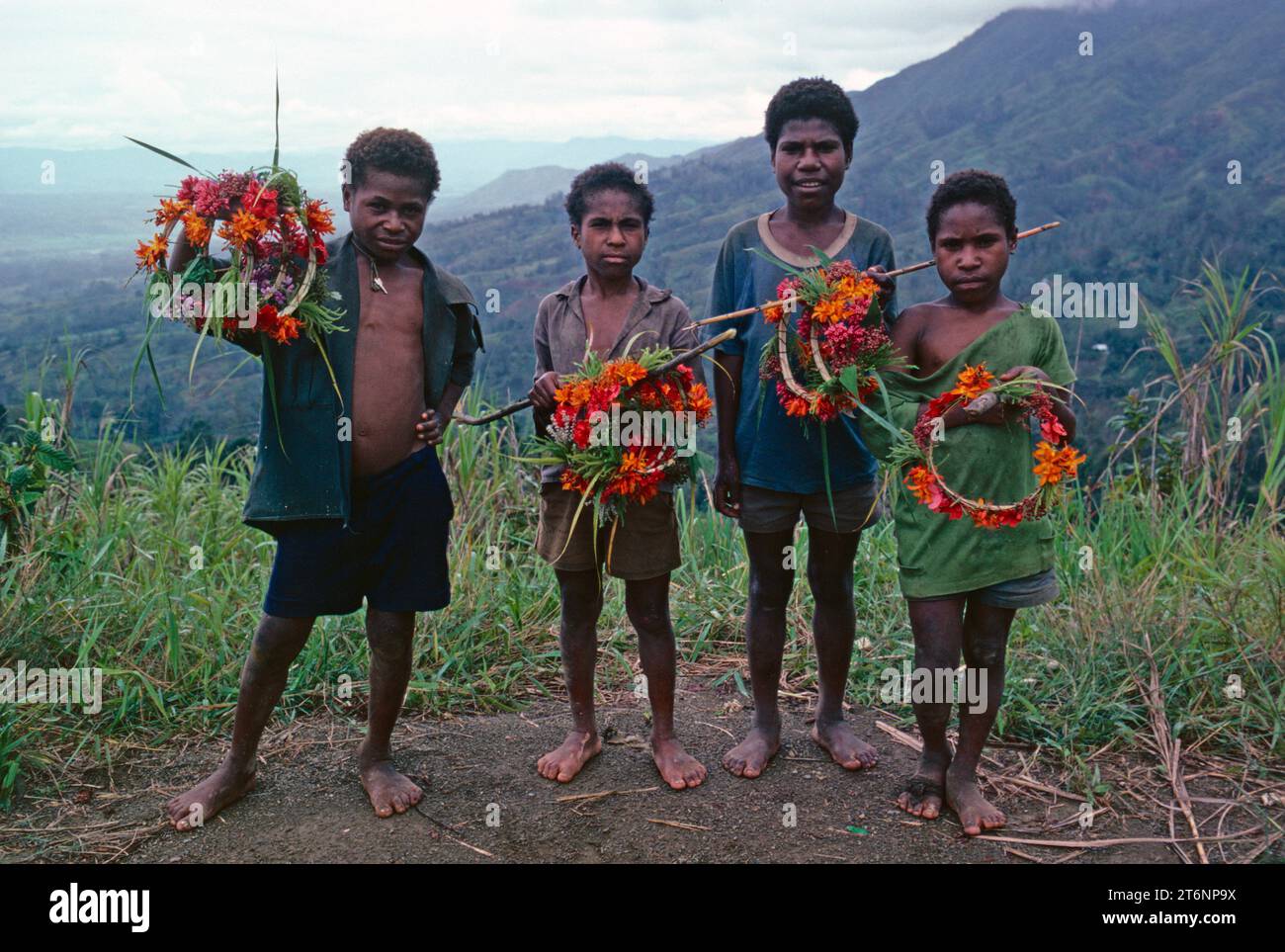 Papouasie-Nouvelle-Guinée. Southern Highlands. Des enfants locaux tenant des cerceaux de fleurs sauvages qu'ils ont fabriqués. Banque D'Images