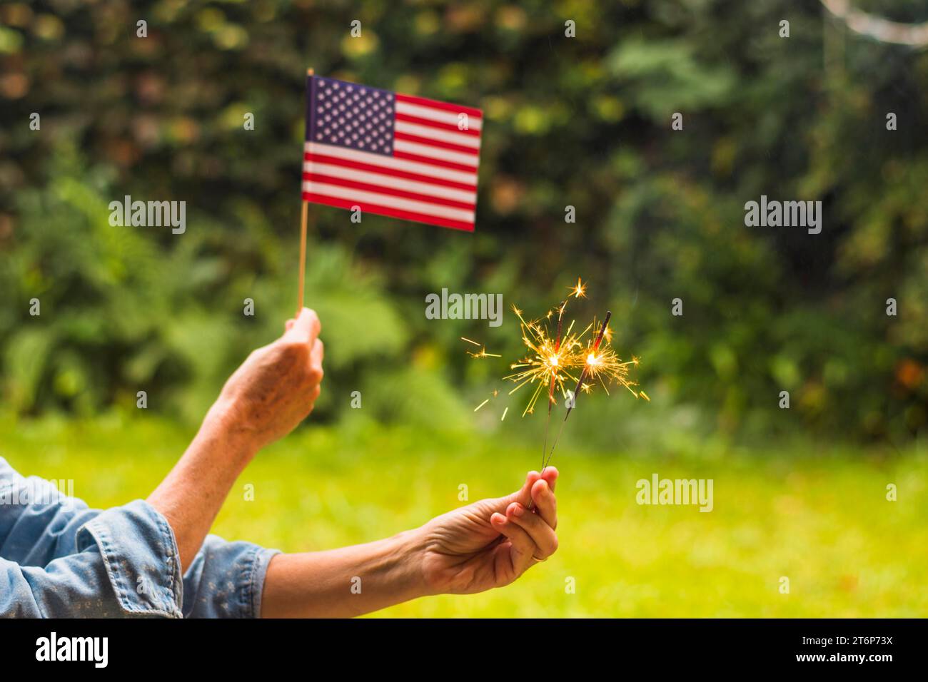 Close up femme célébrant le jour de l'indépendance tenant des étincelles de feu de drapeau des états-unis Banque D'Images