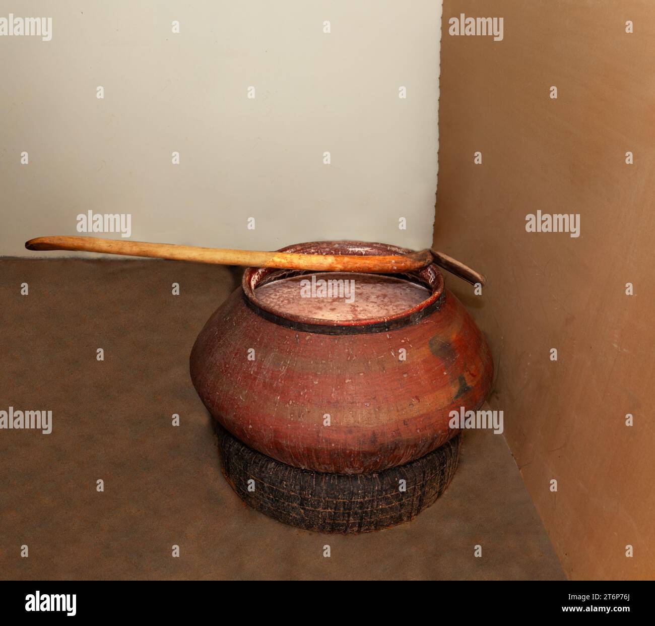 bière traditionnelle africaine dans une argile mise en fermentation à l'ombre dans une pièce fraîche avec une énorme cuillère en bois pour mélanger Banque D'Images