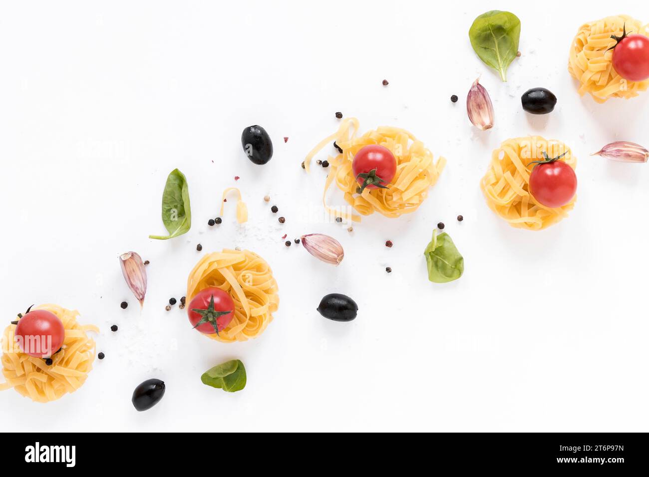 Pâtes crues fettuccine tomate cerise olive noir gousse d'ail feuilles de basilic isolé fond blanc Banque D'Images