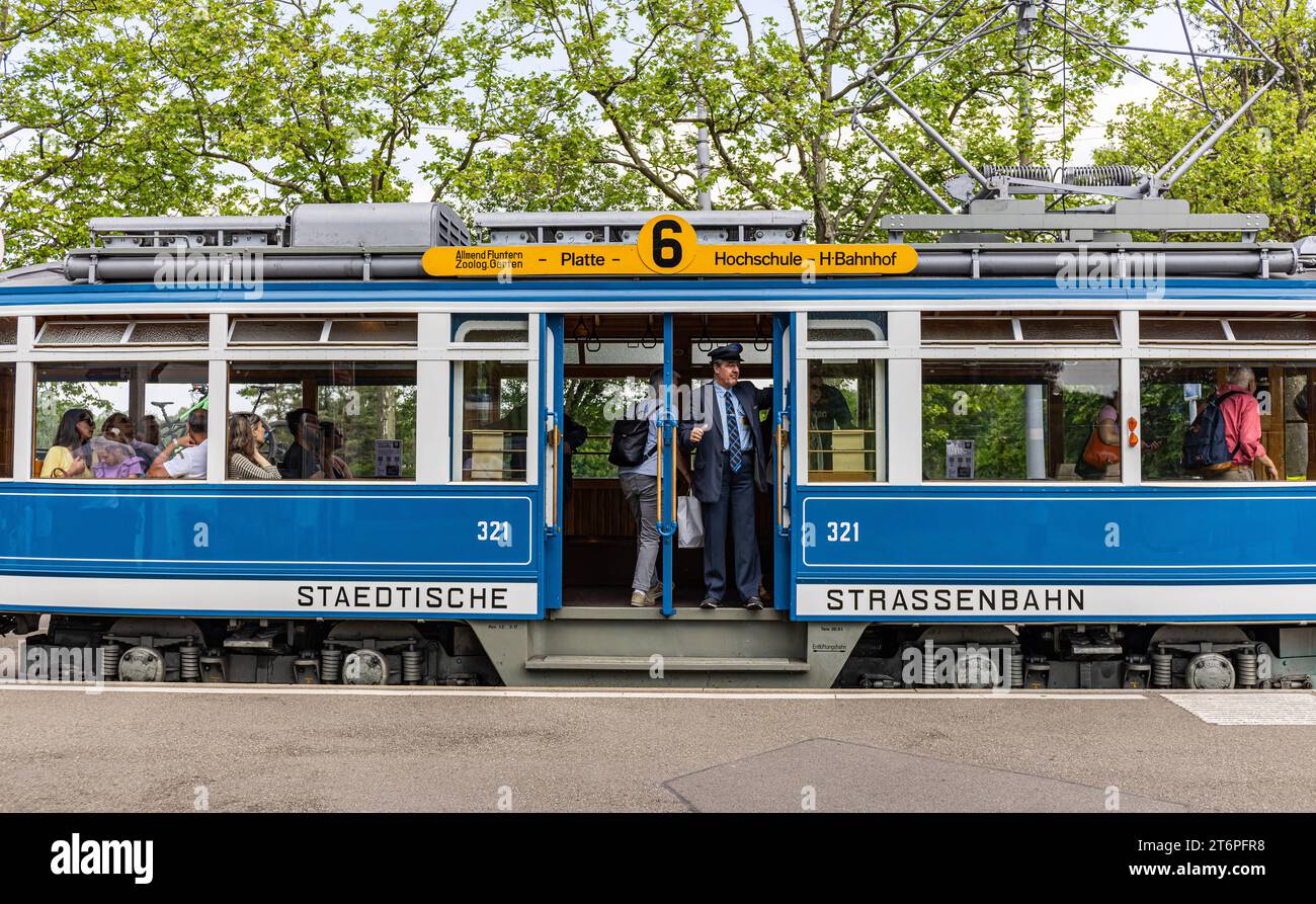 DAS Zürcher Tram - Elefant Ein Kontrolleur schaut ob alle Passagiere eingestiegen sind. DAS war in der Zeit des trams StStZ ce 4/4 321, welches 1930 an die Städtische Strasssenbahn Zürich abgeliefert wurde üblich. Besser bekannt ist das Tram unter dem Übername Elefant . 1966 wurde es ausrangiert und steht seit 1975 als Museumstram im Dienst der VBZ. Hier ist es auf der Linie 6 zwischen Zürich Hauptbahnhof und dem Zürich Zoo, anlässlich des Jubiläumsevents 175 Jahre Eisenbahn in der Schweiz im Einsatz. Zürich, Schweiz, 21.05.2022 *** le tramway de Zurich Elefant un inspecteur vérifie si tous Banque D'Images