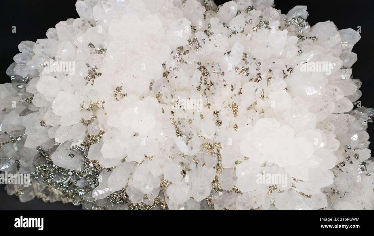 Druse de cristal de roche avec inclusions de pyrite. quartz blanc avec pyrite gros plan sur fond noir. Spécimen géologique de pierre semi-précieuse, sommet vi Banque D'Images