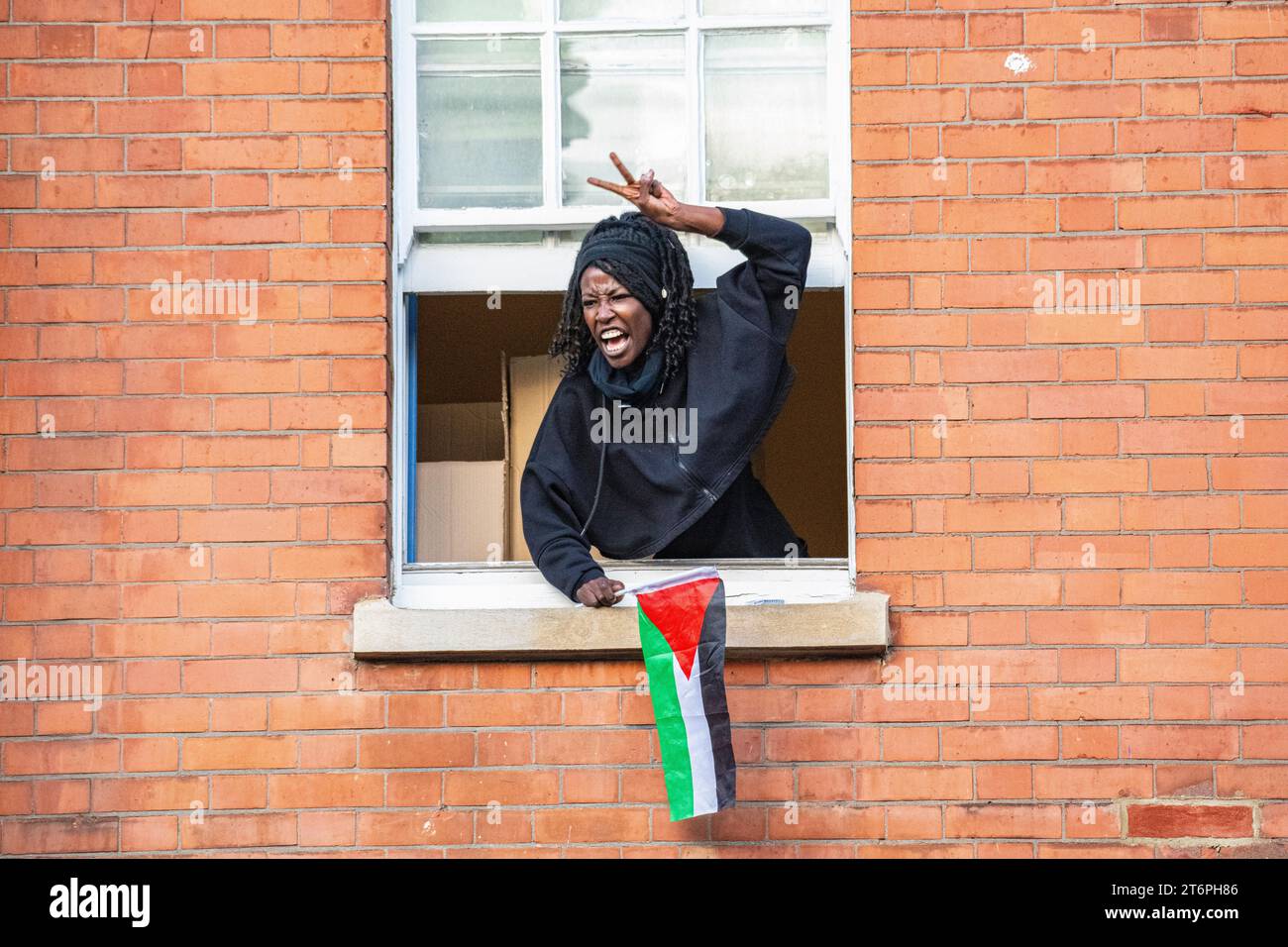 Londres, Royaume-Uni, -11 novembre 2023. Une femme crie de sa fenêtre à 300 000 partisans palestiniens marchant à travers Londres Banque D'Images