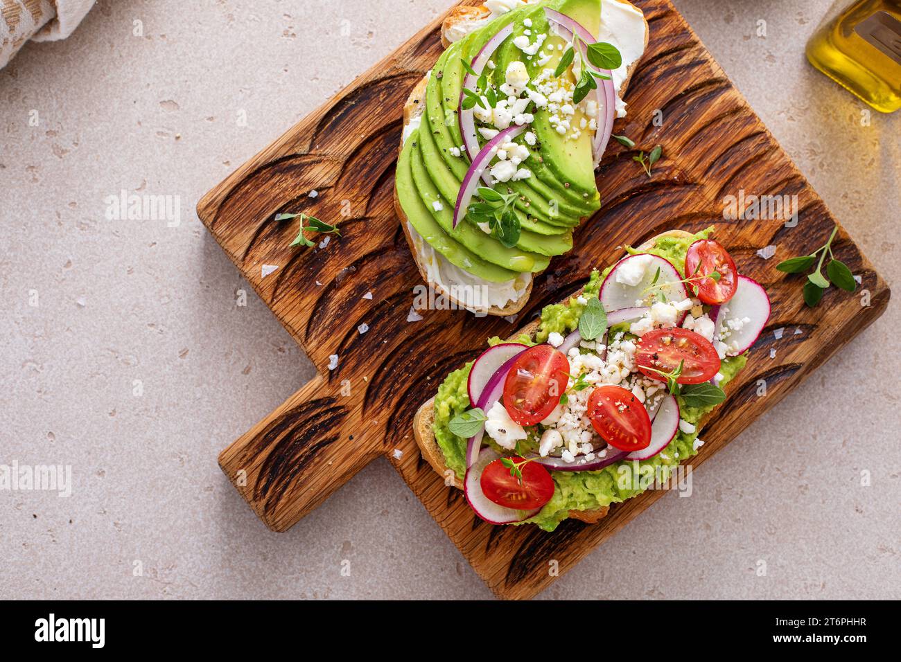 Toasts d'avocat avec radis, tomates et feta garnis d'huile d'olive, idée de petit déjeuner sain Banque D'Images