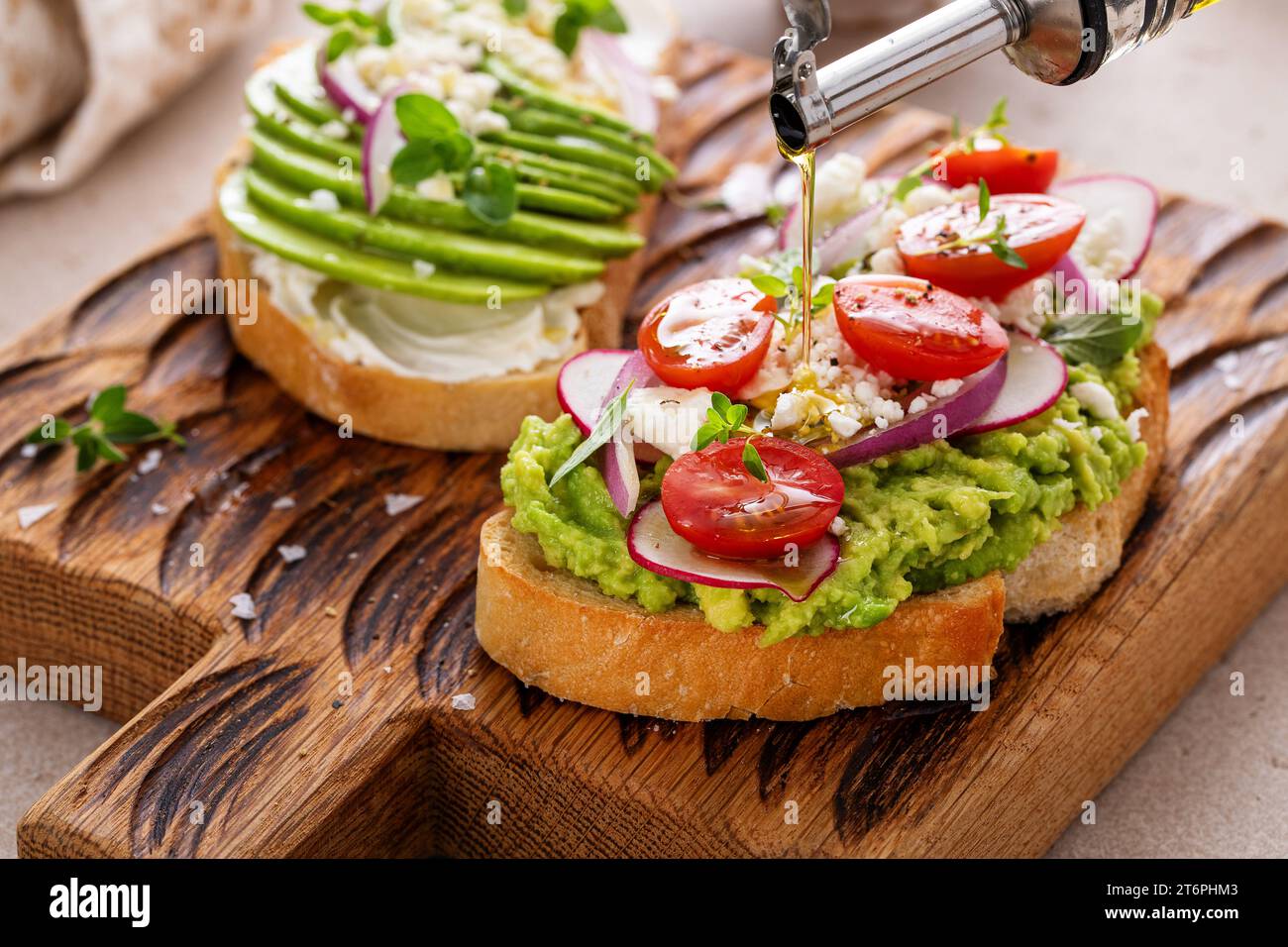 Toasts d'avocat avec radis, tomates et feta garnis d'huile d'olive, idée de petit déjeuner sain Banque D'Images