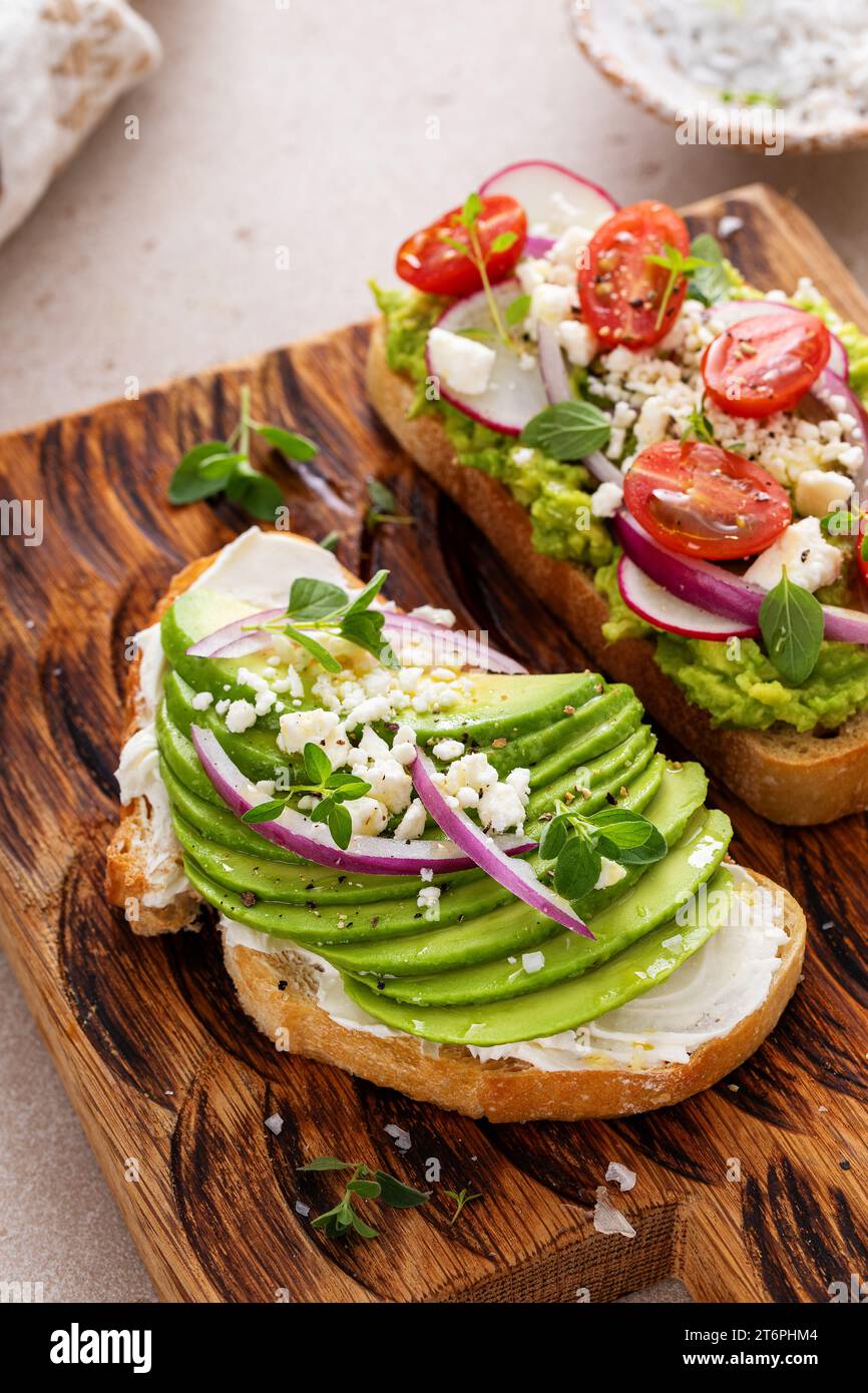 Toasts d'avocat avec radis, tomates et feta garnis d'huile d'olive, idée de petit déjeuner sain Banque D'Images