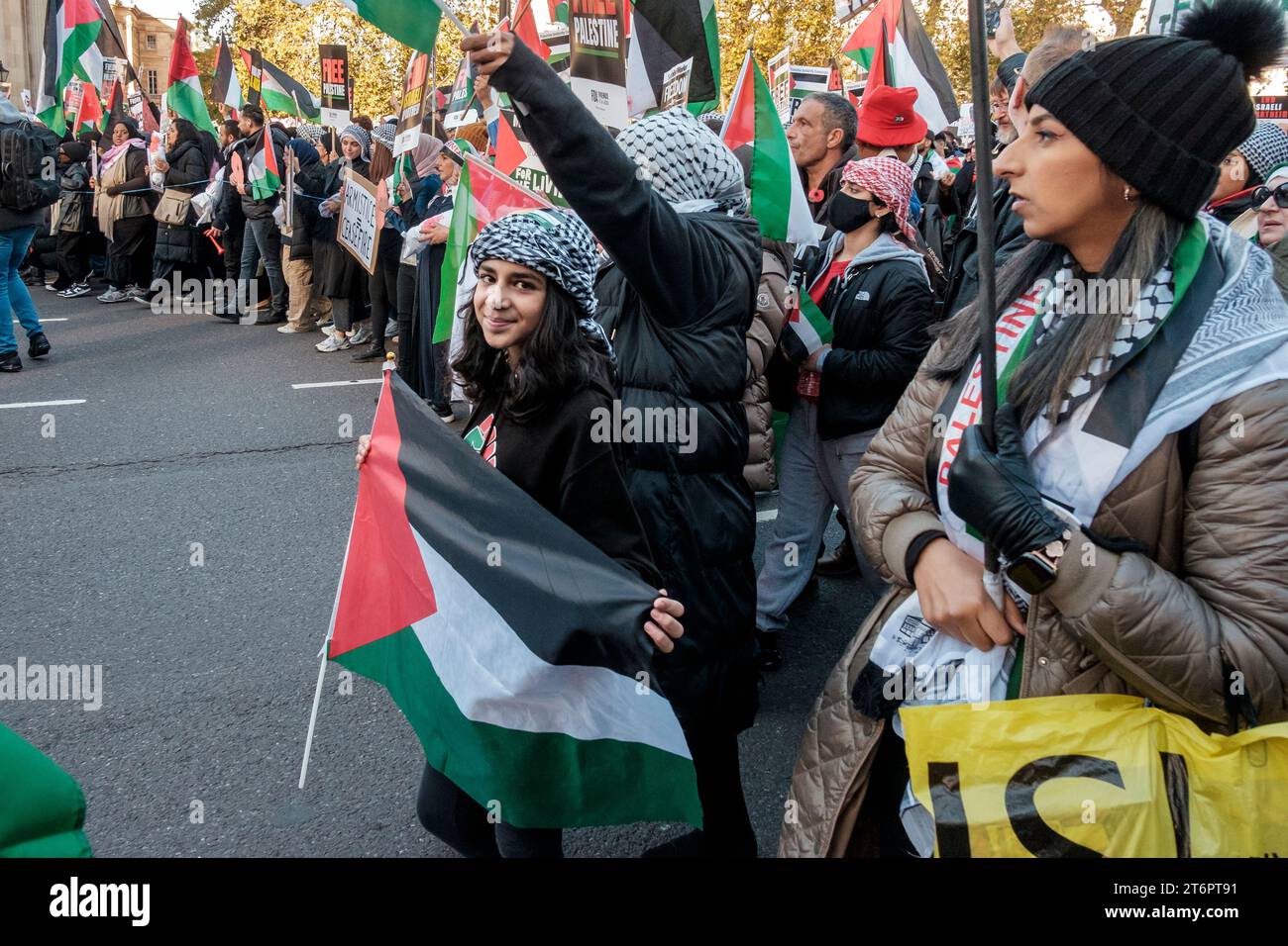 11 novembre 2023, Londres, Royaume-Uni. Des centaines de milliers de personnes défilent dans le centre de Londres pour protester contre le bombardement continu de Gaza par Israël. Les organisateurs du rassemblement, la Palestine Solidarity Campaign, exigent un cessez-le-feu immédiat. Photo : une jeune fille porte un drapeau palestinien le long du parcours de la marche. Banque D'Images
