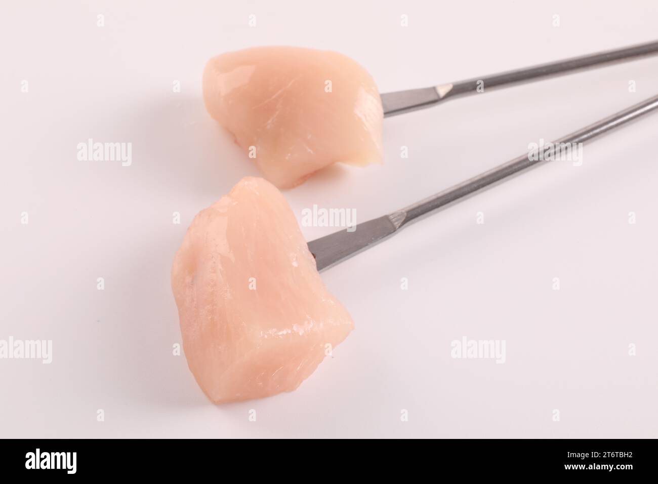 Fourchettes à fondue avec morceaux de viande crue isolés sur blanc Banque D'Images
