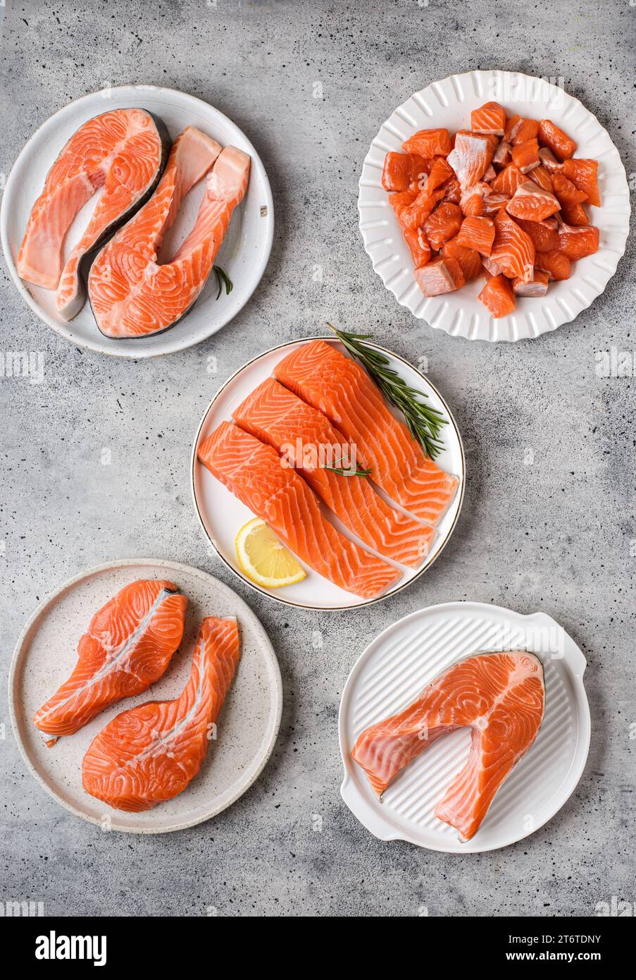 différents types de saumon cru sur fond gris dans une assiette - tranches, filets sur la peau, médaillons et steaks de saumon . Photo de haute qualité Banque D'Images