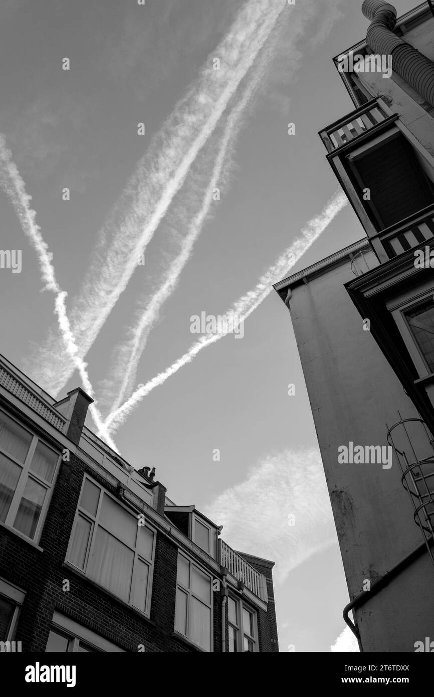 Photographie en noir et blanc du ciel et des maisons avec des toits et des traces de Jets or plane, pays-Bas, la Haye. Banque D'Images