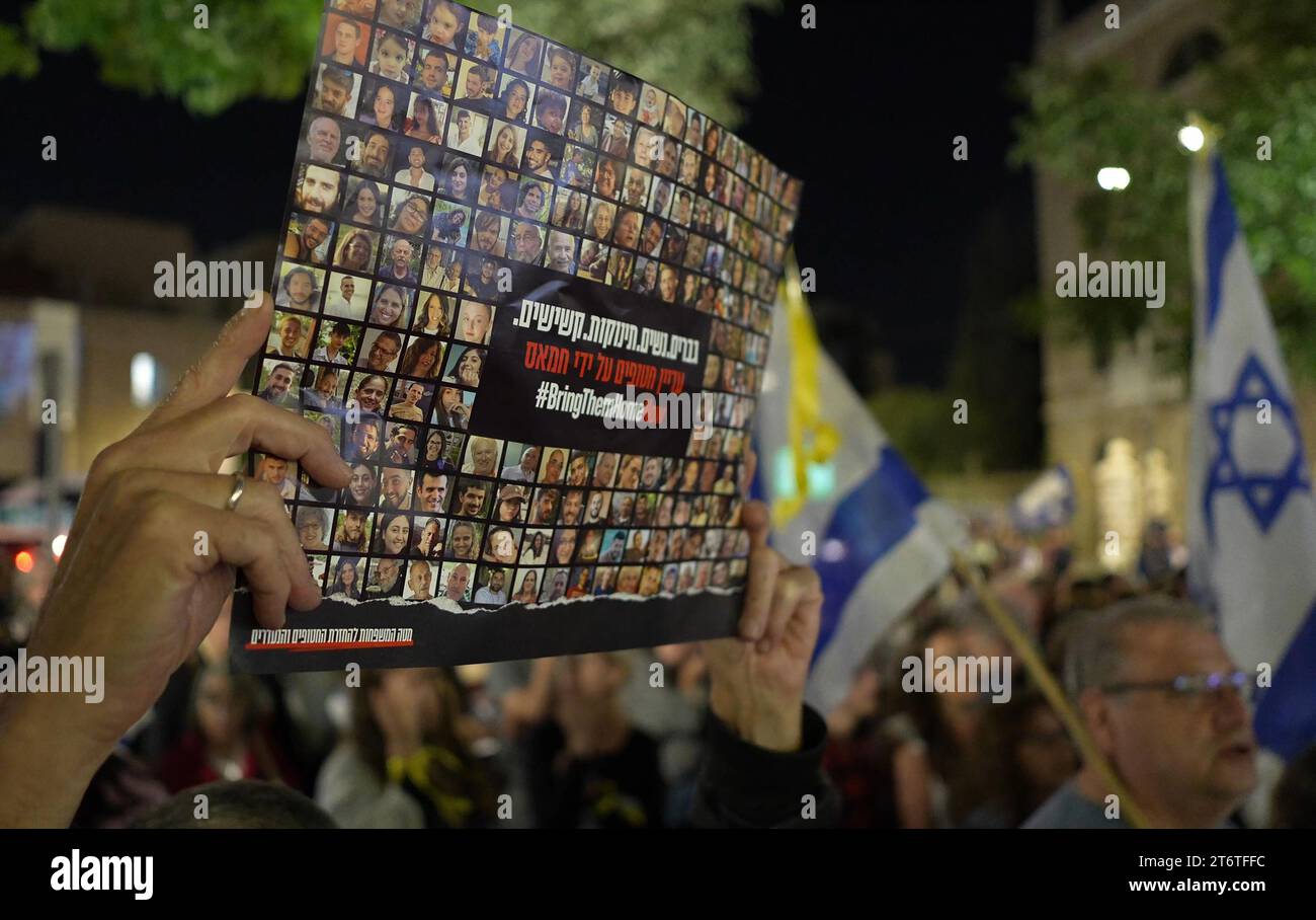 Un homme tient une pancarte avec des photos d’Israéliens retenus en otage par le Hamas alors que les gens chantent l’hymne national lors d’une manifestation pour exiger que le Premier ministre israélien Benjamin Netanyahu obtienne la libération des otages israéliens enlevés par des militants palestiniens et actuellement détenus dans la bande de Gaza le 11 novembre, 2023 à Jérusalem. Un mois après les attaques du Hamas du 7 octobre, l'armée du pays a poursuivi son bombardement continu de la bande de Gaza et a lancé une invasion terrestre pour vaincre le groupe militant qui gouverne le territoire palestinien. Banque D'Images Un homme tient une pancarte avec des photos d’Israéliens retenus en otage par le Hamas alors que les gens chantent l’hymne national lors d’une manifestation pour exiger que le Premier ministre israélien Benjamin Netanyahu obtienne la libération des otages israéliens enlevés par des militants palestiniens et actuellement détenus dans la bande de Gaza le 11 novembre, 2023 à Jérusalem. Un mois après les attaques du Hamas du 7 octobre, l'armée du pays a poursuivi son bombardement continu de la bande de Gaza et a lancé une invasion terrestre pour vaincre le groupe militant qui gouverne le territoire palestinien. Banque D'Images