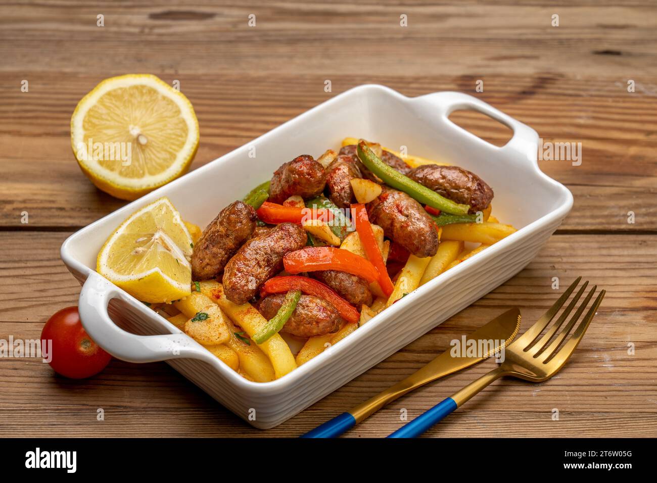 Une assiette en céramique blanche remplie de steak grillé et de légumes frais, accompagnée d'une fourchette en métal jaune Banque D'Images