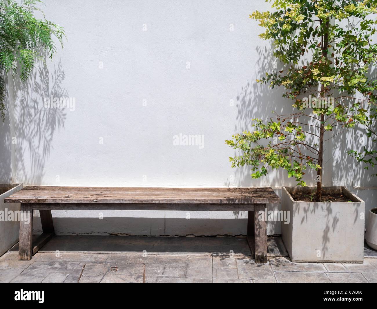 Vide vieux long banquette en bois avec personne sur un mur blanc près de la décoration des grands pots en béton à l'extérieur du bâtiment. Banque D'Images