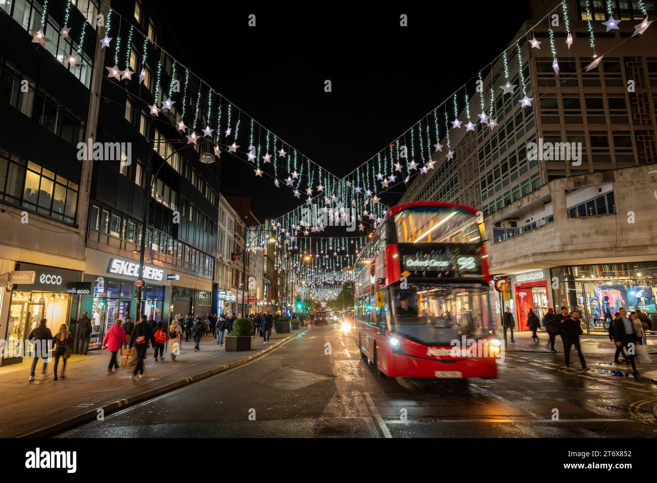 Londres, Royaume-Uni - novembre 8 2023 : Oxford Street, une célèbre rue commerçante du centre de Londres avec des lumières de Noël et un bus rouge londonien avec flou de mouvement. Banque D'Images