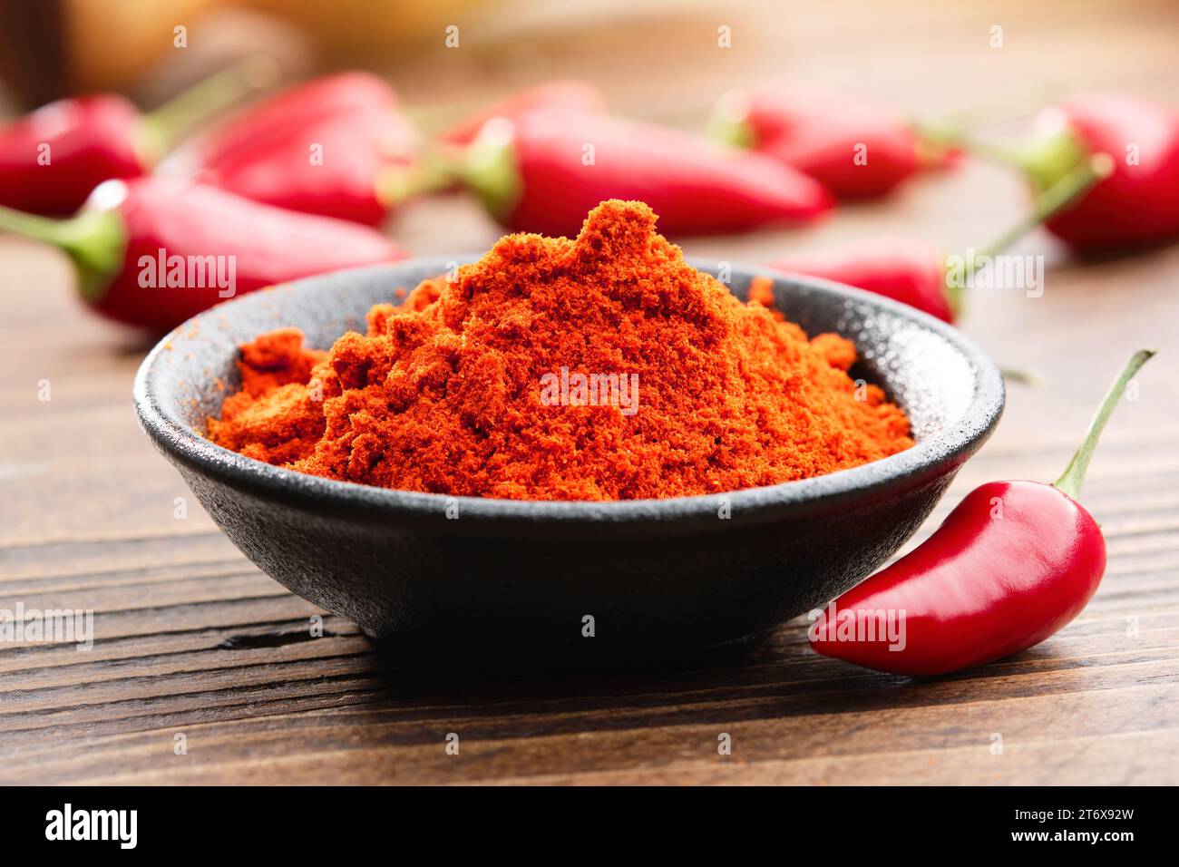 Bol de piment rouge moulu en poudre et dosettes entières de piment rouge rouge sur fond. Banque D'Images