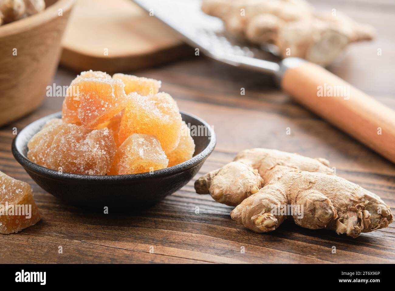 Morceaux de gingembre confit et racines de gingembre sur la table de cuisine en bois. Bonbons sains. Banque D'Images