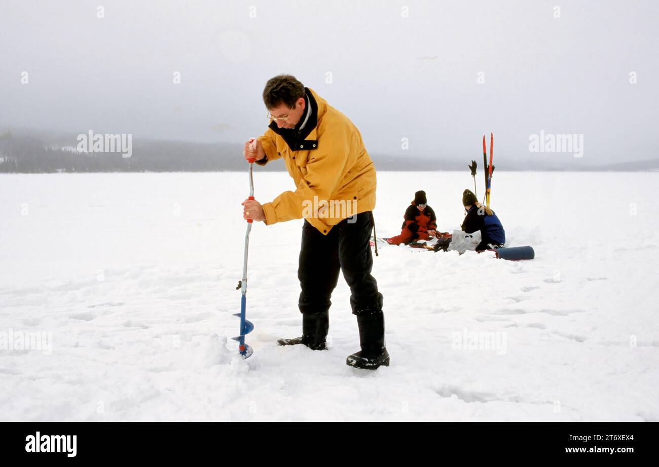 TROMSO, NORVÈGE - JANVIER 14 2022 : pêcheurs pêchant sur glace sur un lac gelé en hiver avec canne à pêche ou canne à pêche, tarière à glace et équipement pour la pêche Banque D'Images