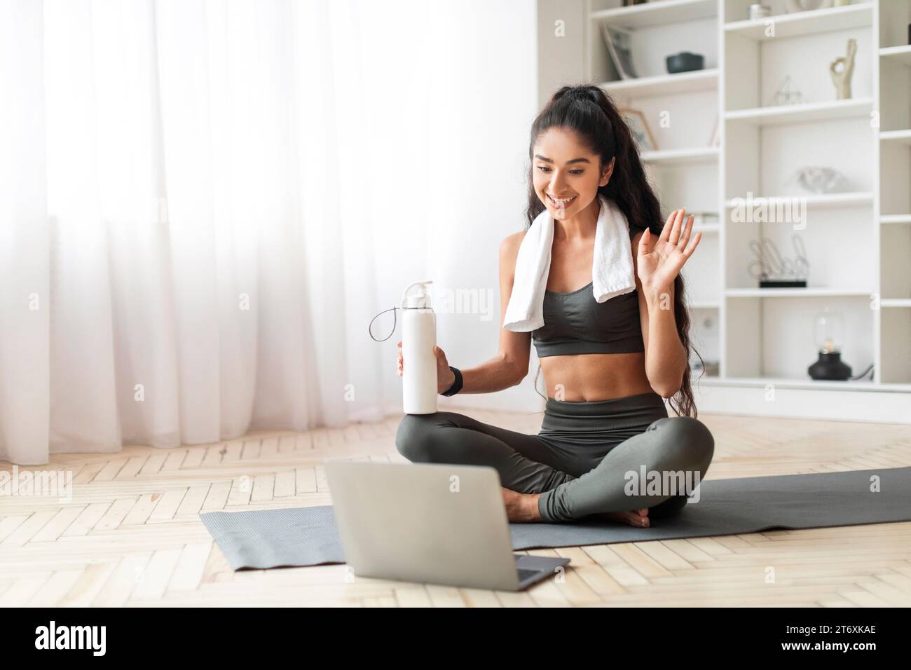Joyeuse jeune femme indienne buvant de l'eau après l'entraînement à la maison Banque D'Images