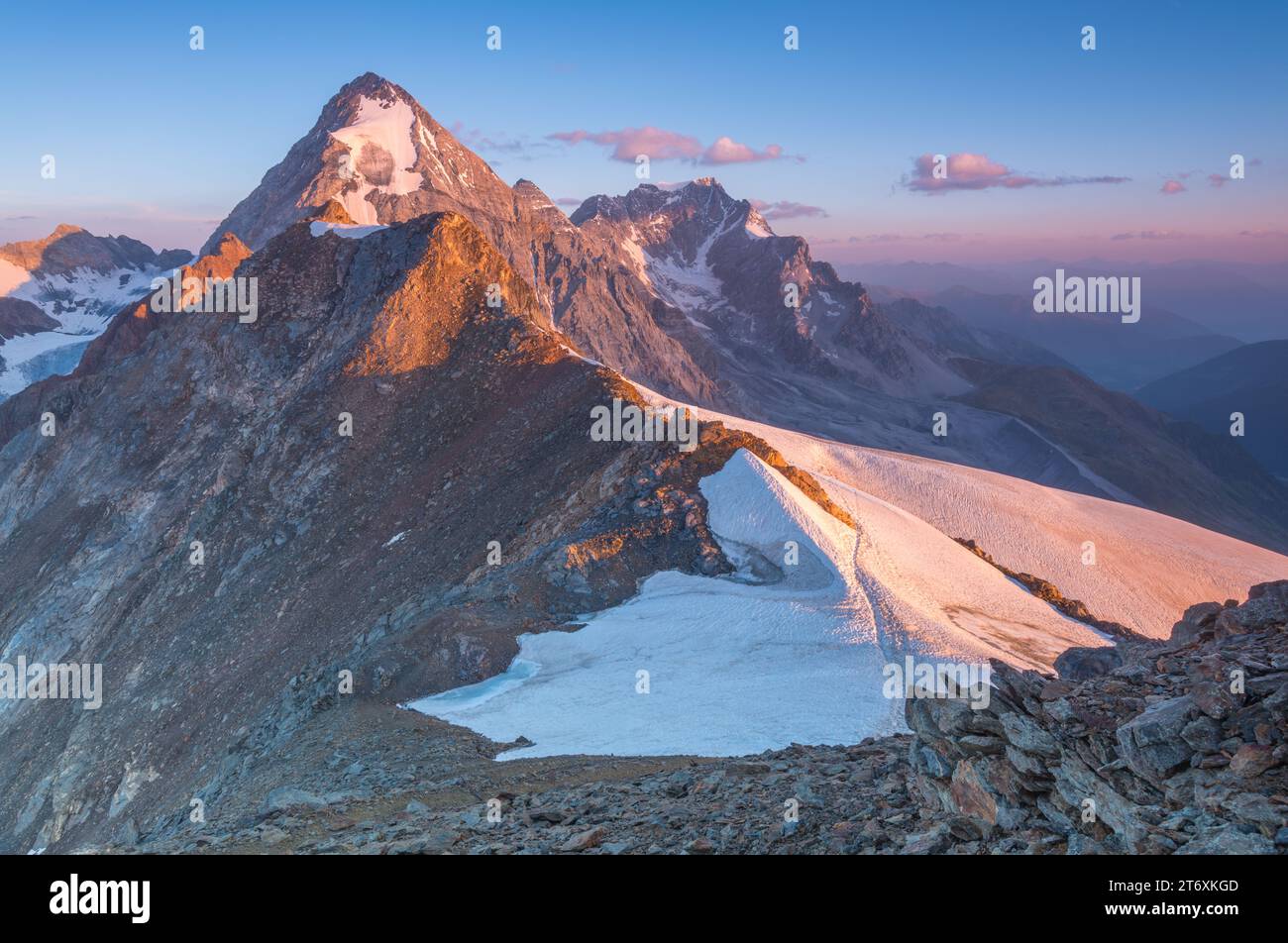 La montagne Gran Zebrù est orangée lors d'un magnifique lever de soleil alpin. Aube au sommet avec vue sur les sommets et les champs de neige. Banque D'Images