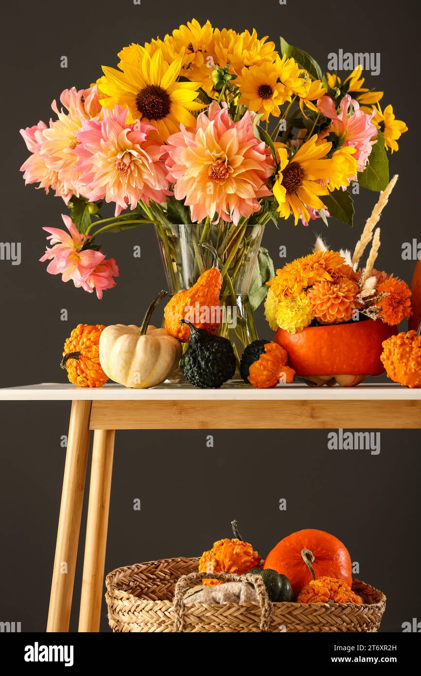 Composition d'automne avec de belles fleurs et citrouilles sur la table de console sur fond gris foncé Banque D'Images