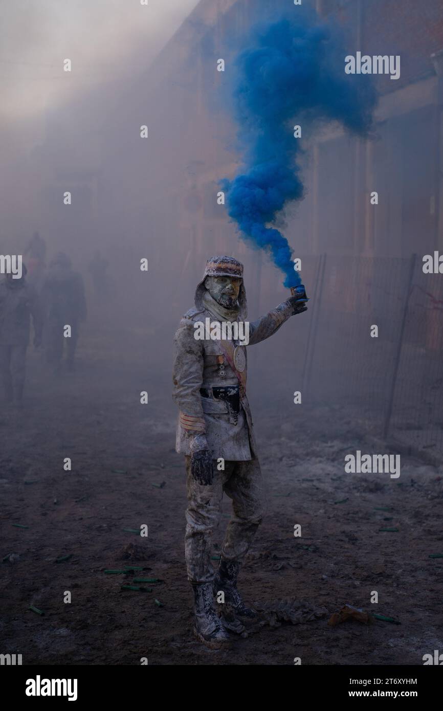 IBI, Espagne - 28 décembre 2022 : Homme habillé en soldat regardant la caméra avec une bombe de fumée bleue à la main lors d'une bataille traditionnelle de farine à Ibi, en Espagne Banque D'Images