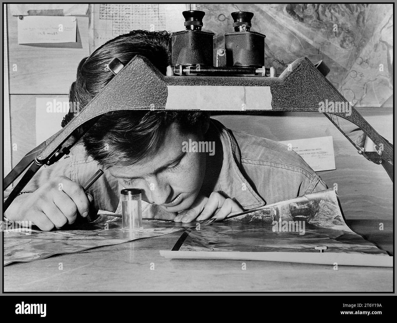 GUERRE DE CORÉE CINQUIÈME ARMÉE DE L'AIR renseignement de reconnaissance aérienne avec une photographie d'une position de canon communiste devant lui, le sergent James E. Kindseth regarde attentivement à travers sa loupe. 1950 Corée du Sud Banque D'Images
