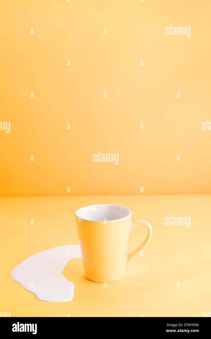 Tasse jaune avec du lait renversé Banque D'Images Tasse jaune avec du lait renversé Banque D'Images