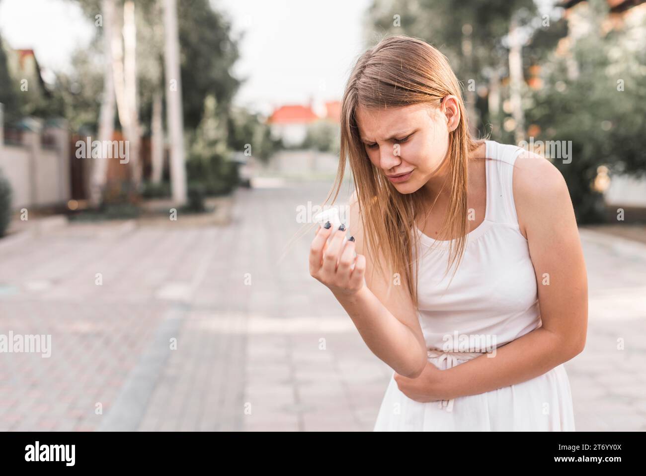 Jeune femme ayant mal à l'estomac tenant la bouteille de pilules blanches Banque D'Images