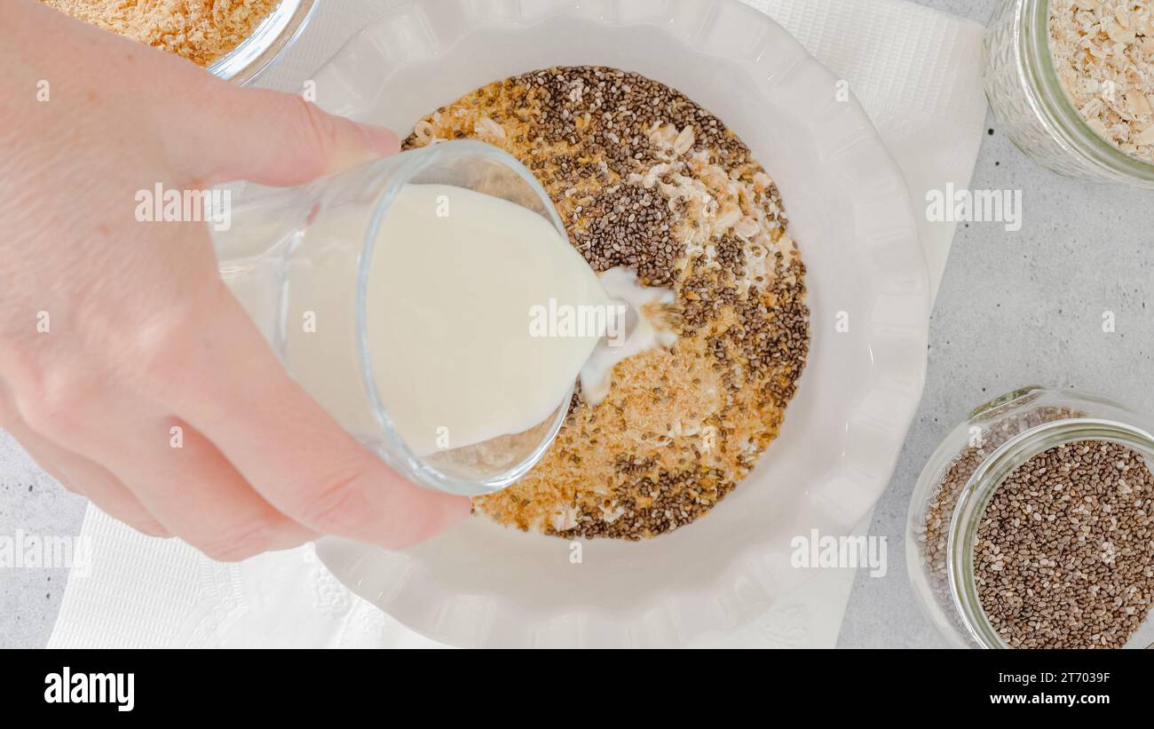 Femme préparant le petit déjeuner. Flocons d'avoine à base d'avoine entière, de farine de lin, de graines de Chia et de lait. Vue rapprochée du dessus Banque D'Images