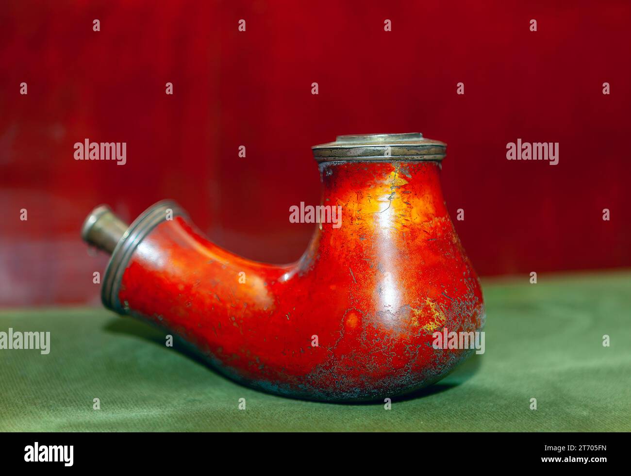 Vieille pipe à fumer sur une nappe verte avec un fond rouge. Tuyau pour fumée altérée par des années d'utilisation Banque D'Images