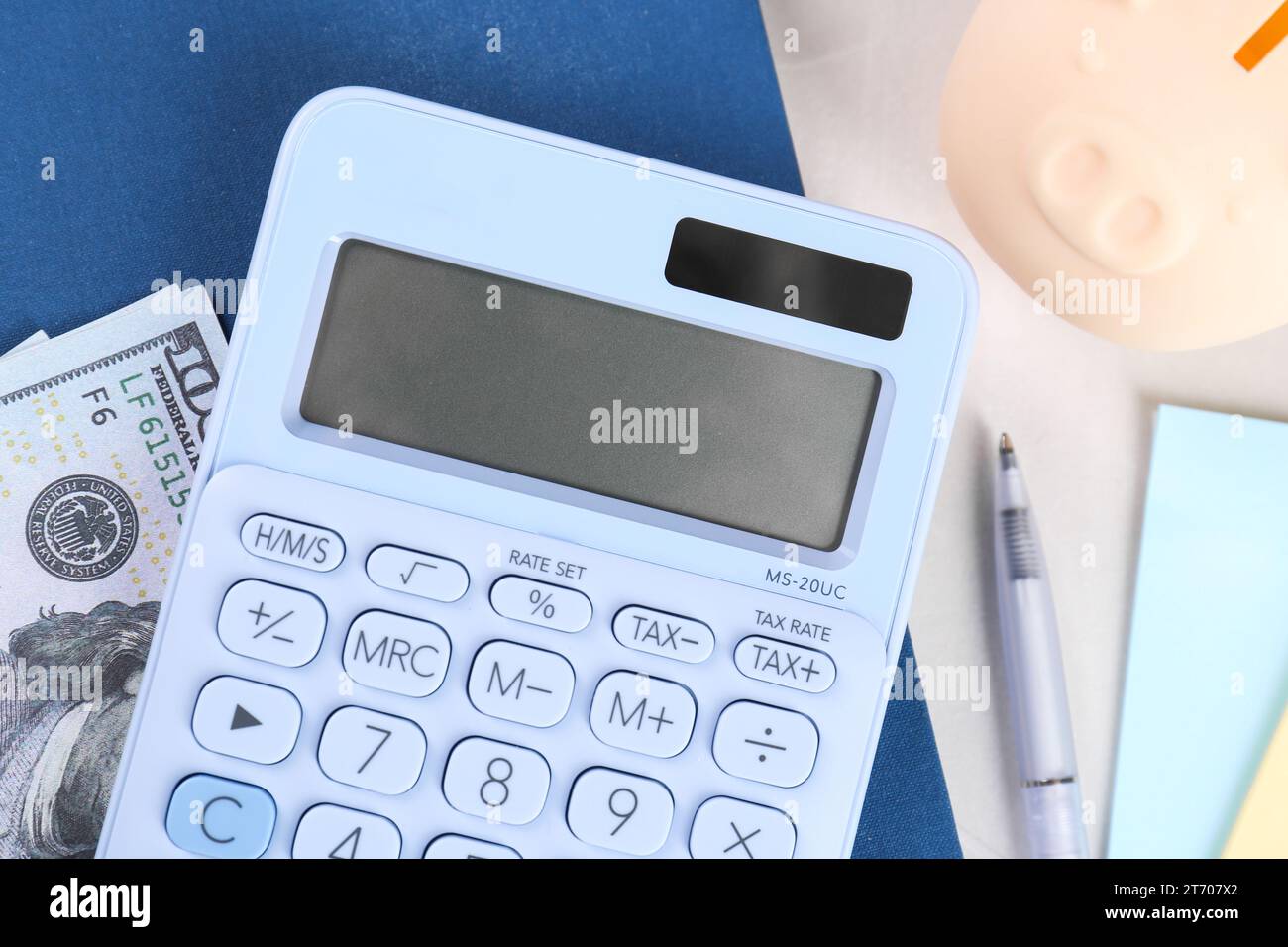 Calculatrice, billet de banque dollar, cahier, stylo et tirelire sur table gris clair, pose à plat. Concept de retraite Banque D'Images