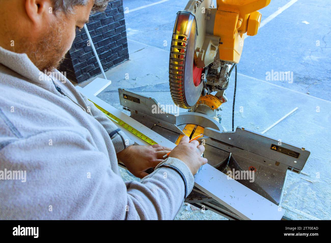 Découpe de moulures de base en bois avec une scie à découper par un ébavureur Banque D'Images