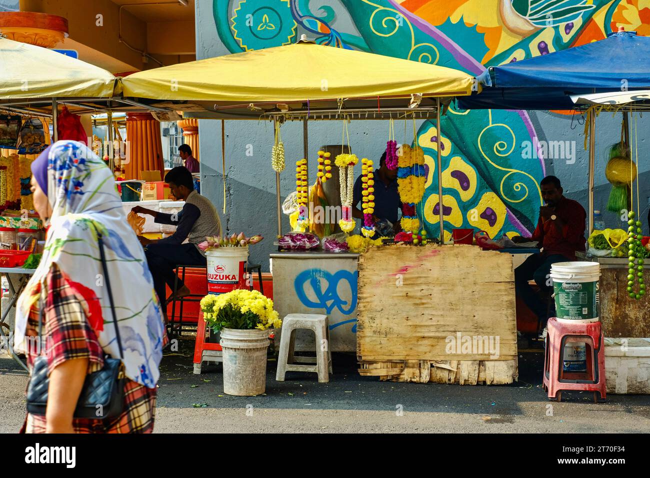 Kuala Lumpur, Malaisie - 18 octobre 2023 : Femme en hijab marchant devant des vendeurs de guirlandes de fleurs au temple Sri Mahamariamman dans Chinatown, près de Petaling St Banque D'Images