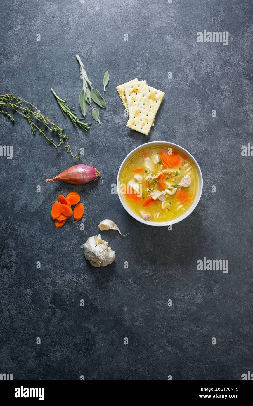 Soupe de nouilles au poulet dans un bol sur fond noir avec des légumes Banque D'Images