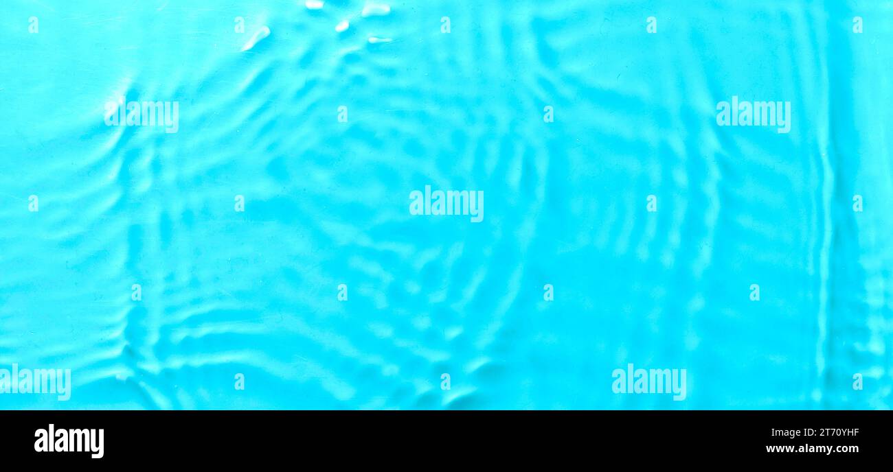 Ondulation d'eau de couleur bleue transparente avec espace de copie. Surface défocalisée et floue avec éclaboussures, bulles et brillance. Banque D'Images