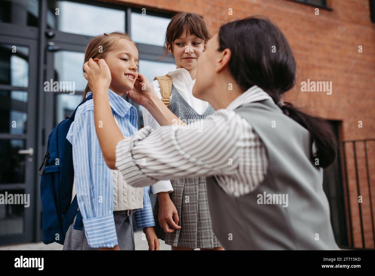 Mère travailleuse et ambitieuse préparant ses filles à l'école, leur disant adieu devant le bâtiment de l'école, et se dirige vers le travail. Concept de Banque D'Images