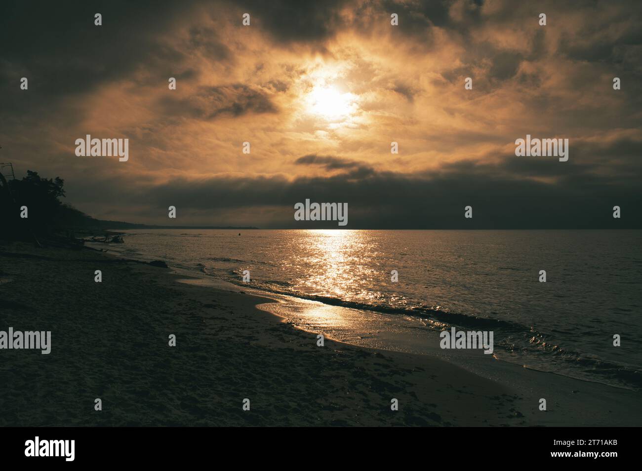 Coucher de soleil sur la plage ouest sur la mer Baltique. Vagues, plage, ciel nuageux et derniers rayons de soleil sur la côte. Photo paysage Banque D'Images