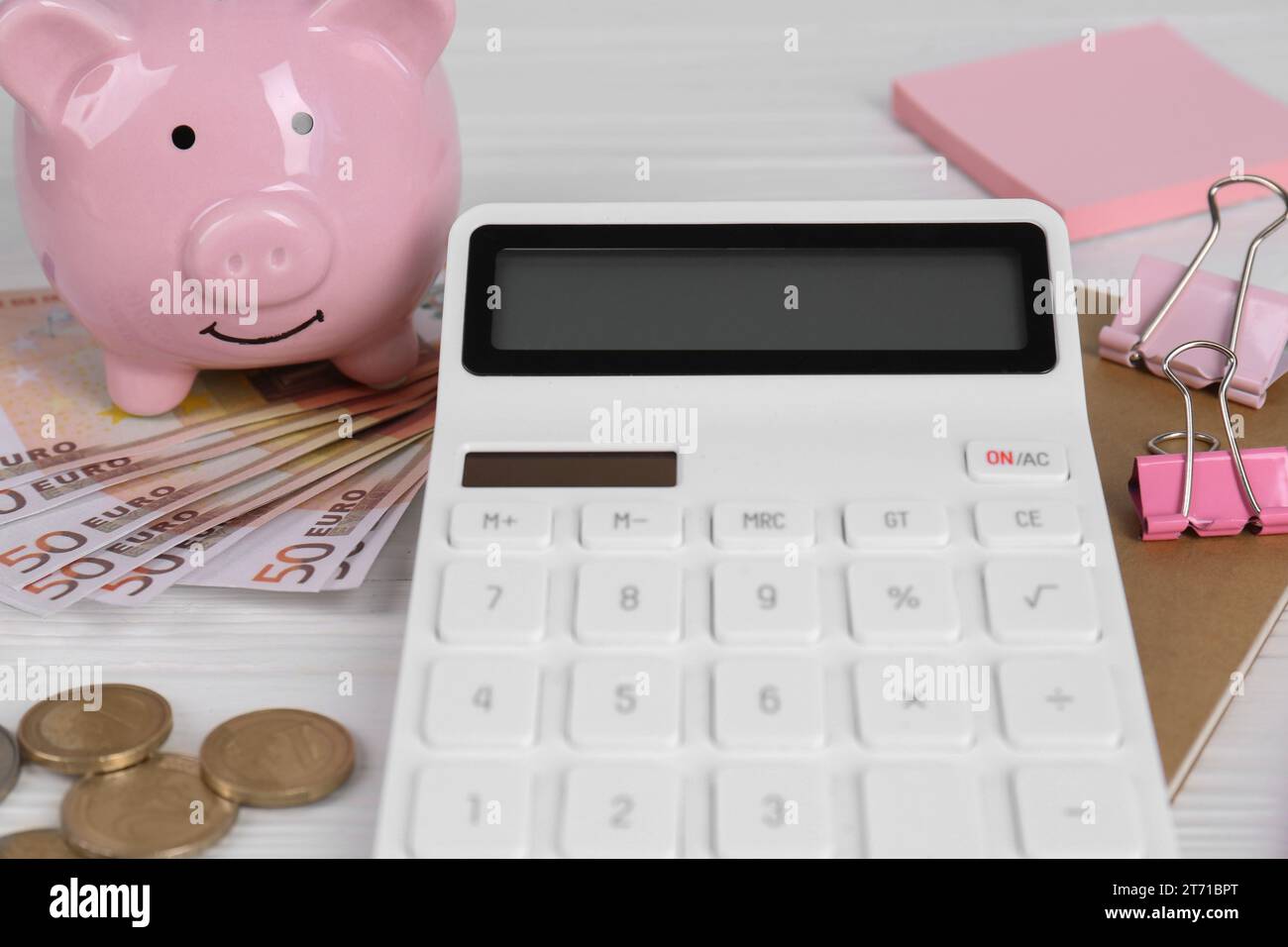 Calculatrice, argent, tirelire, cahier et pinces de reliure sur table en bois blanc, gros plan. Concept de retraite Banque D'Images