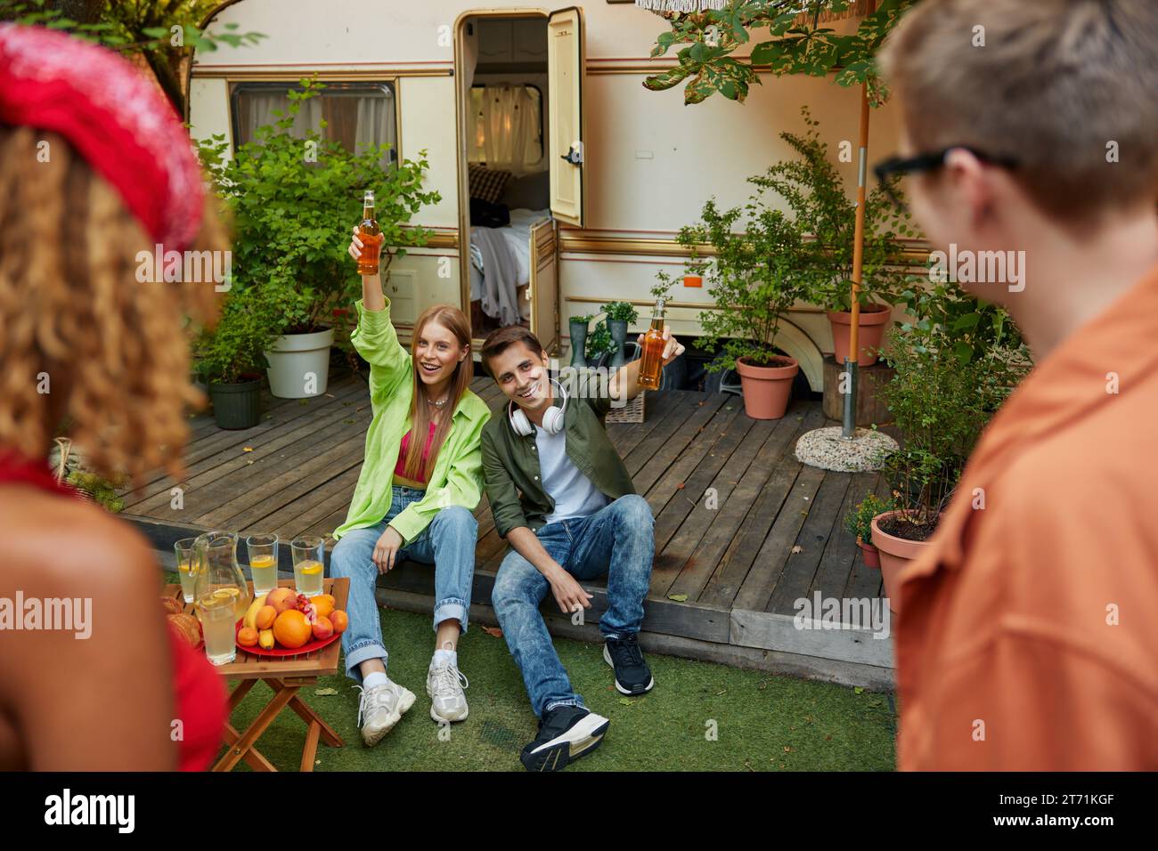 Rire jeune couple partageant repas et boissons avec des amis Banque D'Images