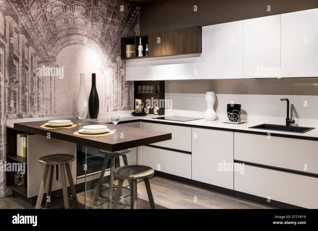 Design intérieur de la cuisine moderne meublée avec placards en bois blanc plate-forme lavabo avec robinet noir appareils modernes table à manger avec tabourets a Banque D'Images