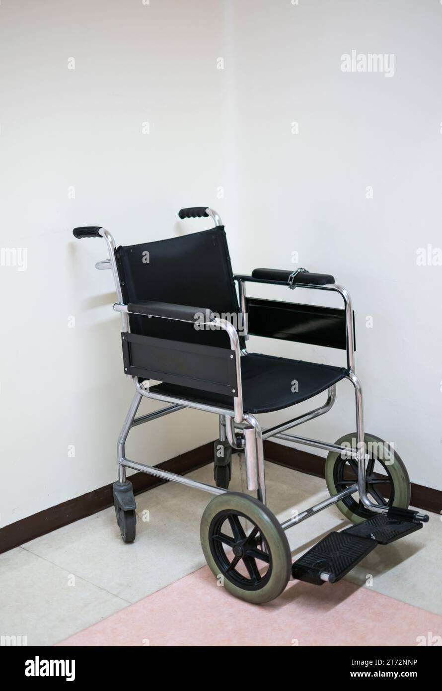 Fauteuil roulant noir sur le sol de l'hôpital avec fond blanc Banque D'Images