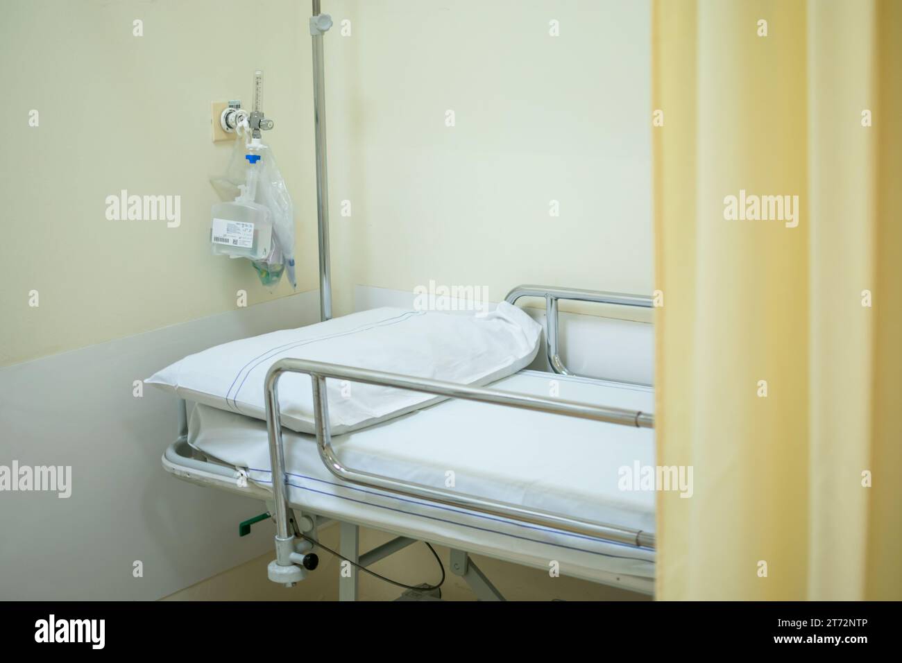 Lit d'hôpital ou civière avec rideau jaune clair et oxygène purifié derrière Banque D'Images