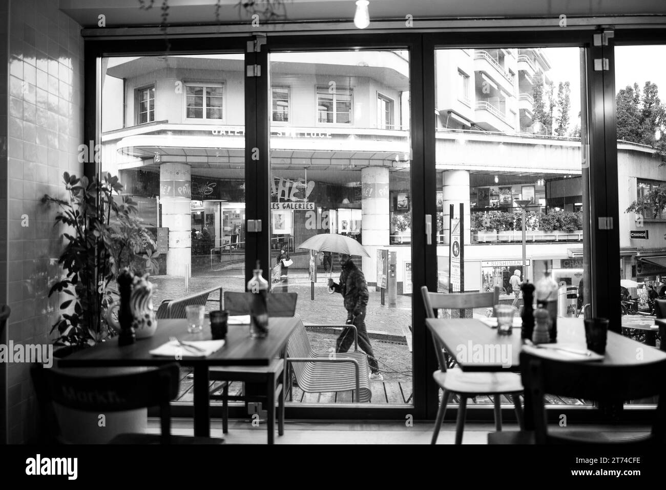 Un homme marche dans une rue de la ville, tenant un parapluie ouvert dans une main et une porte ouverte dans l'autre Banque D'Images