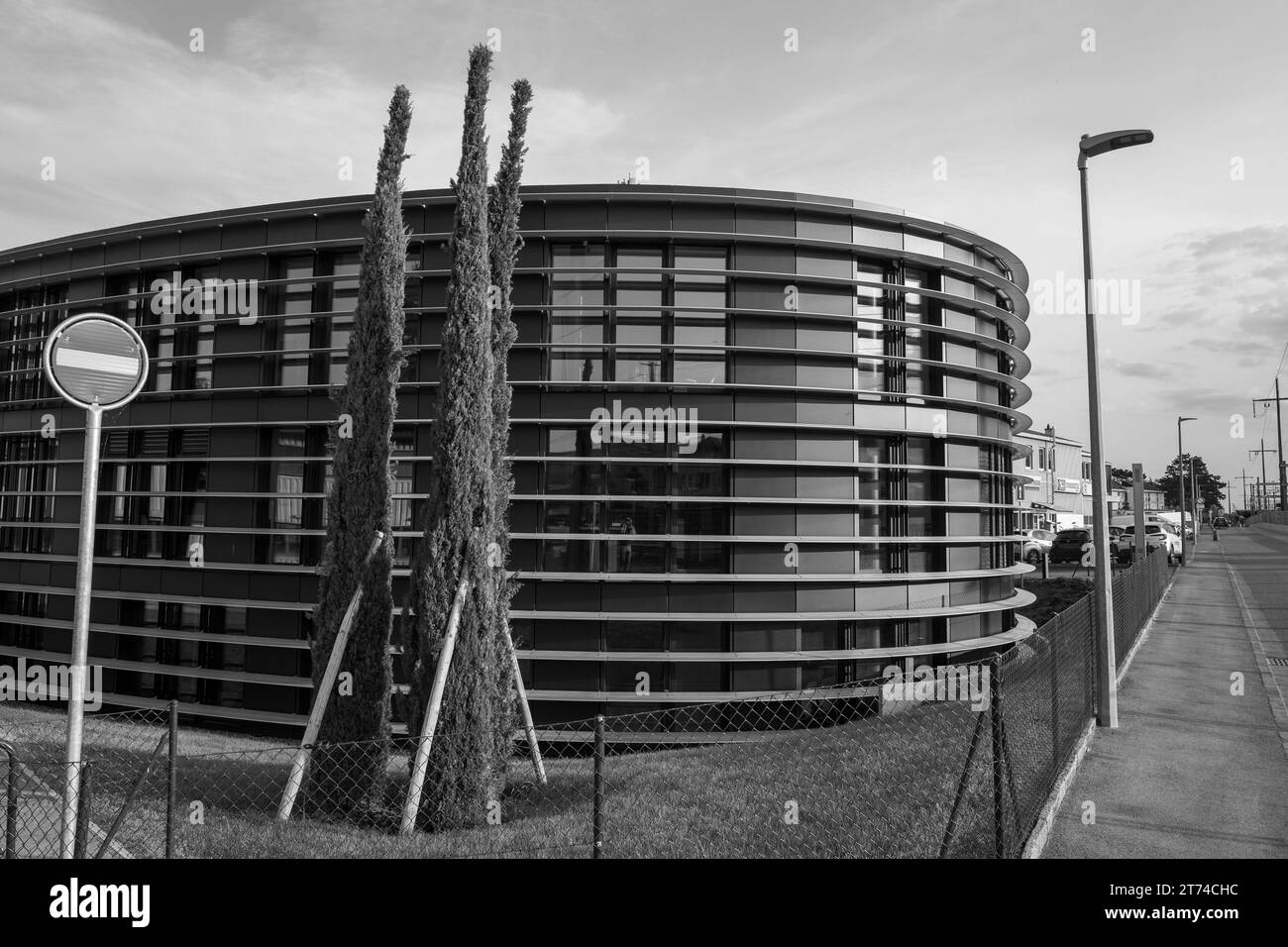 Un bâtiment rond et blanc est situé le long d'une rue, avec une signalisation à côté Banque D'Images