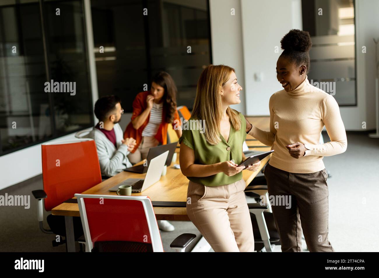 Deux jolies jeunes femmes d'affaires avec tablette numérique dans le bureau moderne Banque D'Images