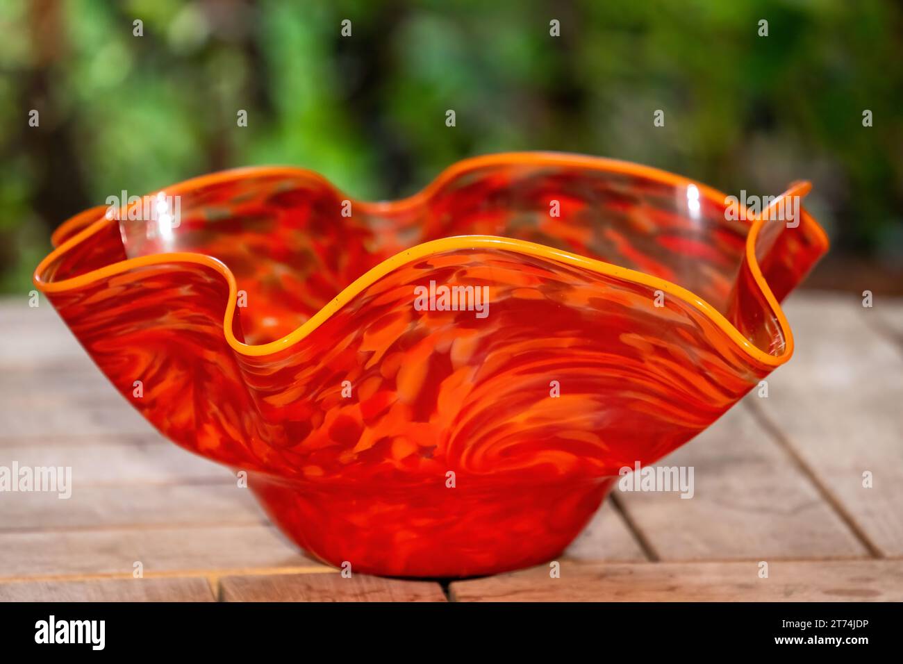 Issaquah, Washington, États-Unis. Soufflé à la main, décoratif, cannelé, grand bol en verre reposant sur une table de patio en bois. Banque D'Images