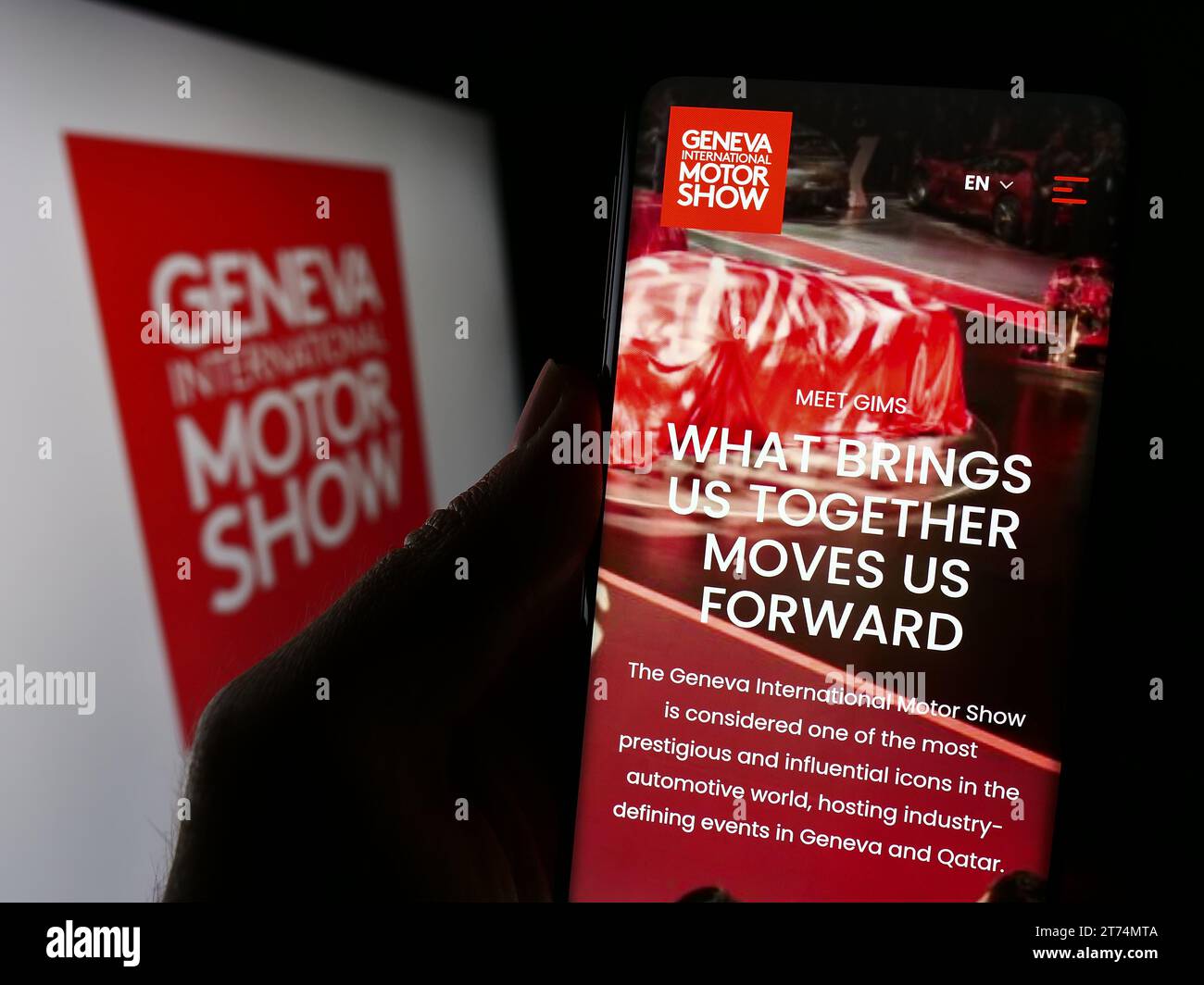 Personne tenant un téléphone portable avec la page Web du salon suisse de l'auto Genève salon international de l'automobile devant le logo. Concentrez-vous sur le centre de l'écran du téléphone. Banque D'Images