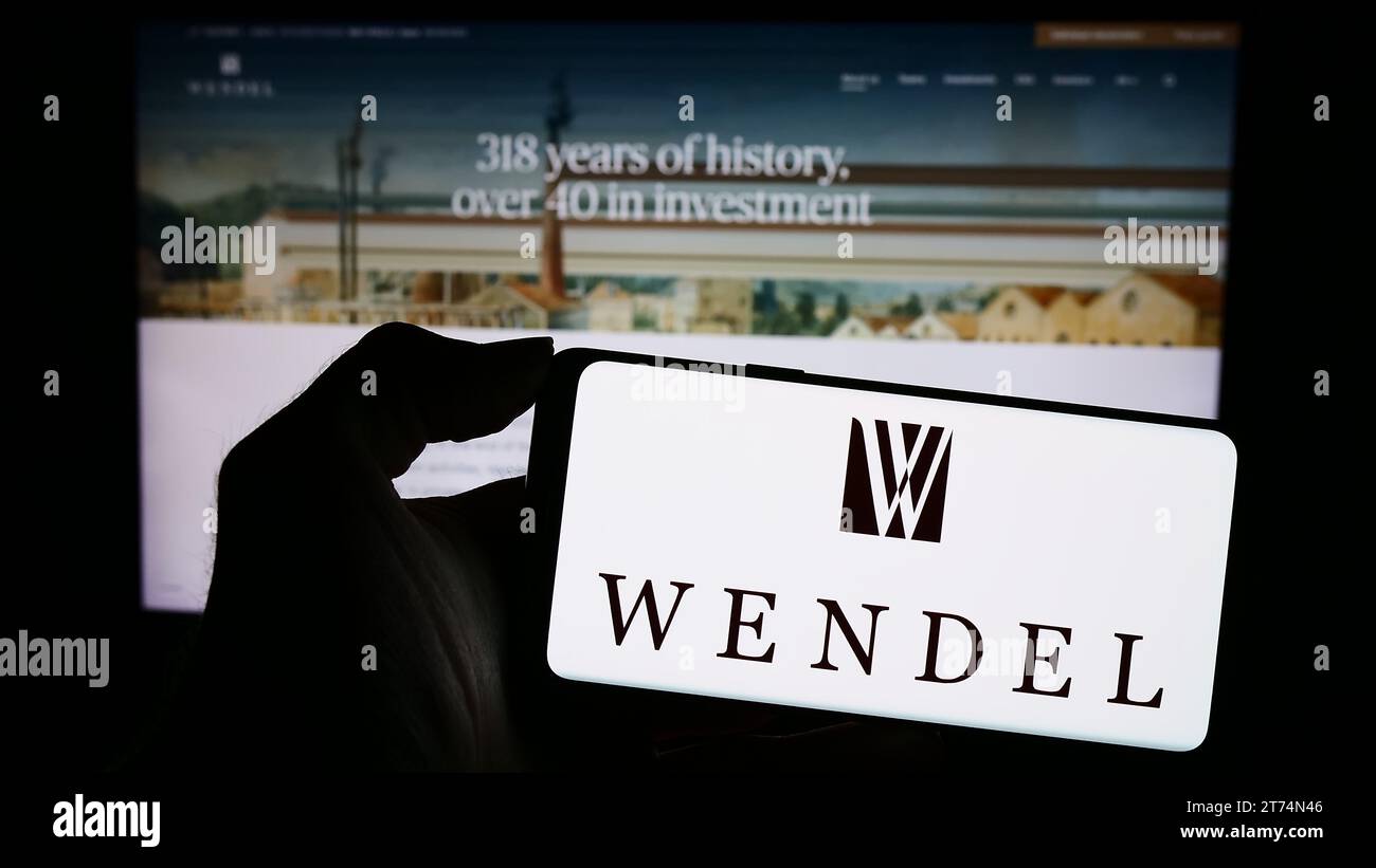 Personne détenant un téléphone portable avec le logo de la société d'investissement française Wendel se devant la page Web de l'entreprise. Concentrez-vous sur l'affichage du téléphone. Banque D'Images