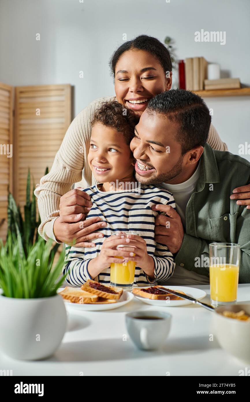 plan vertical de la joyeuse famille afro-américaine serrant chaleureusement les uns les autres à la table du petit déjeuner Banque D'Images